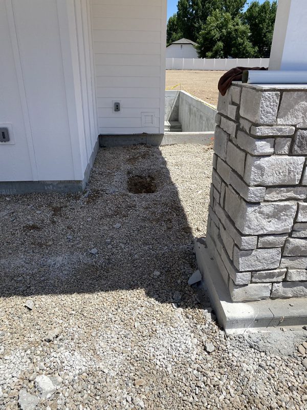 Open soil access point beside a stone porch column