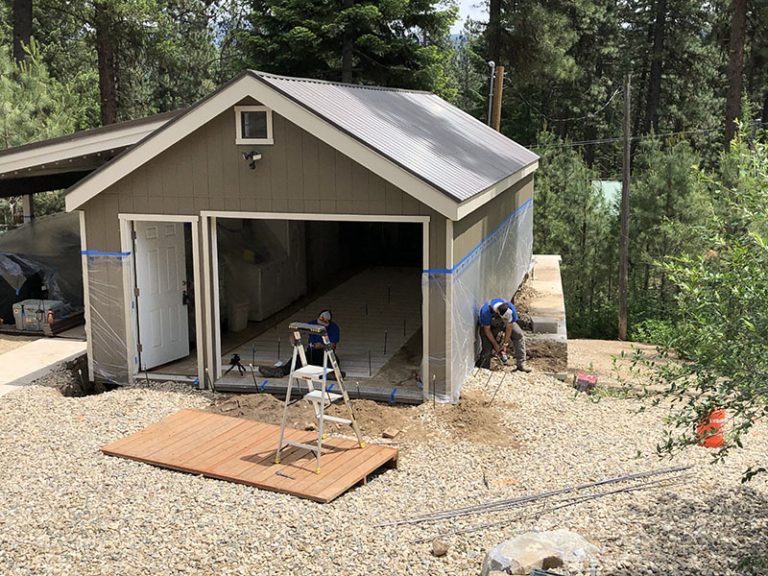 Shed with open garage bay and work equipment