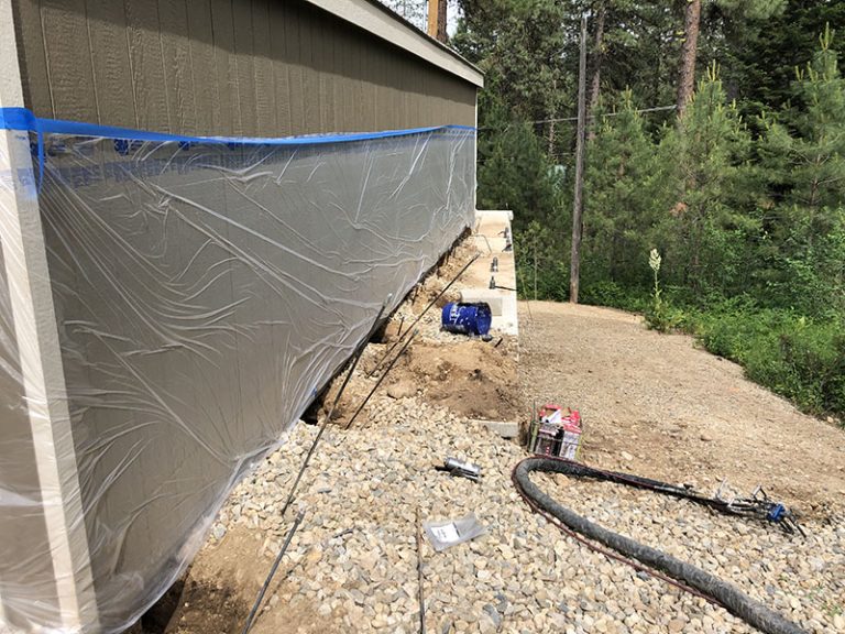 Plastic-protected shed side with injection hoses on gravel
