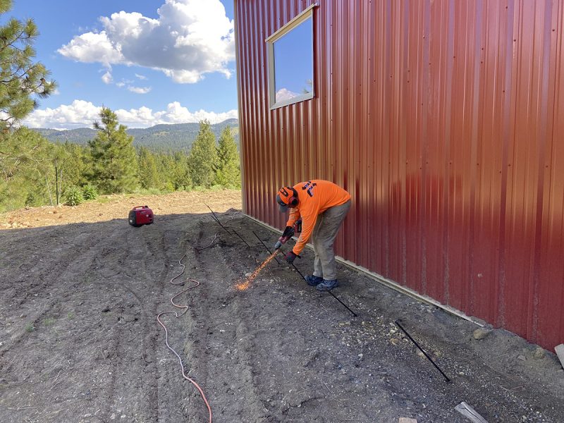 Worker using an injection rod beside the shop foundation