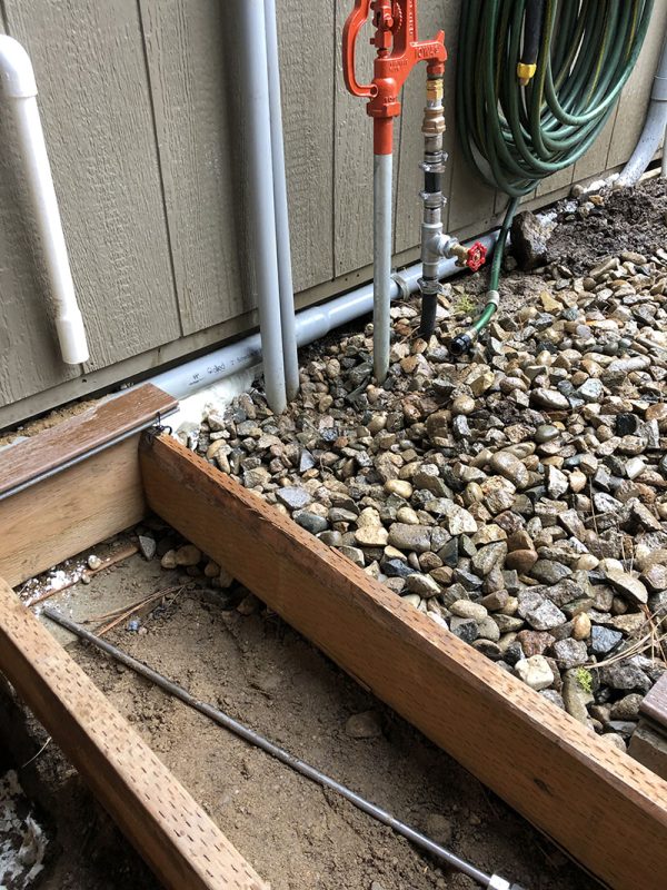 Exposed plumbing beside gravel and formwork