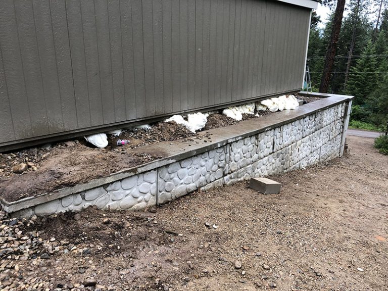 Structural foam visible beneath shed wall above retaining wall