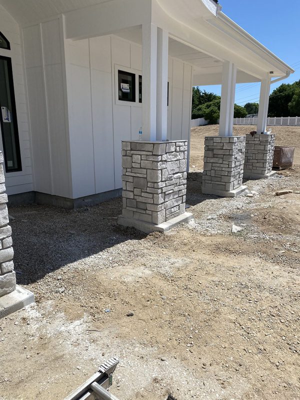 Stone-clad porch columns over unfinished gravel work area