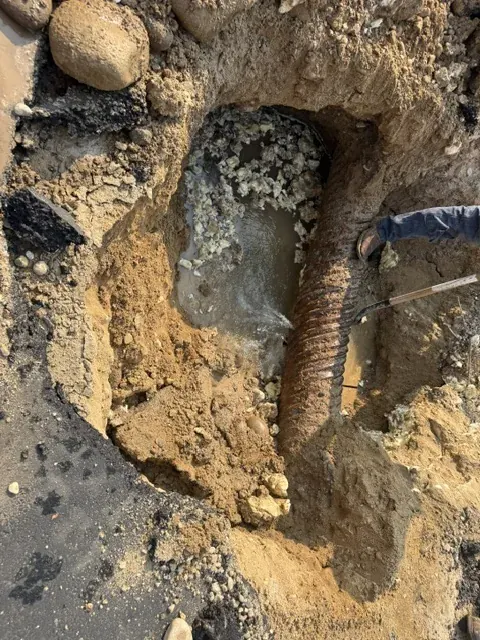 Exposed water line and void beneath asphalt during leak repair